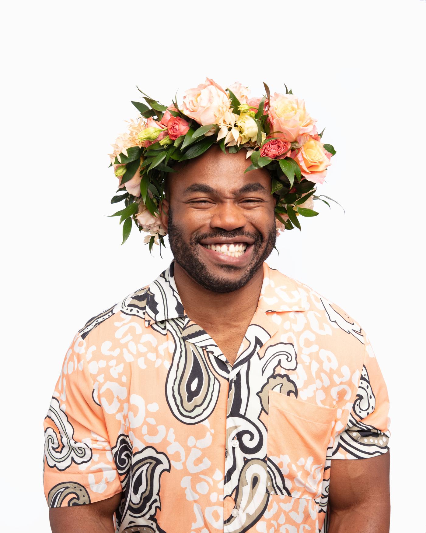 Un home sorrindo cunha coroa de flores