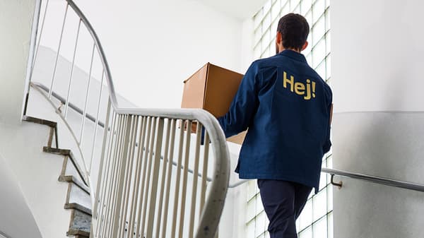 Un home subindo as escaleiras dun bloque de edificios cun paquete de IKEA nas mans