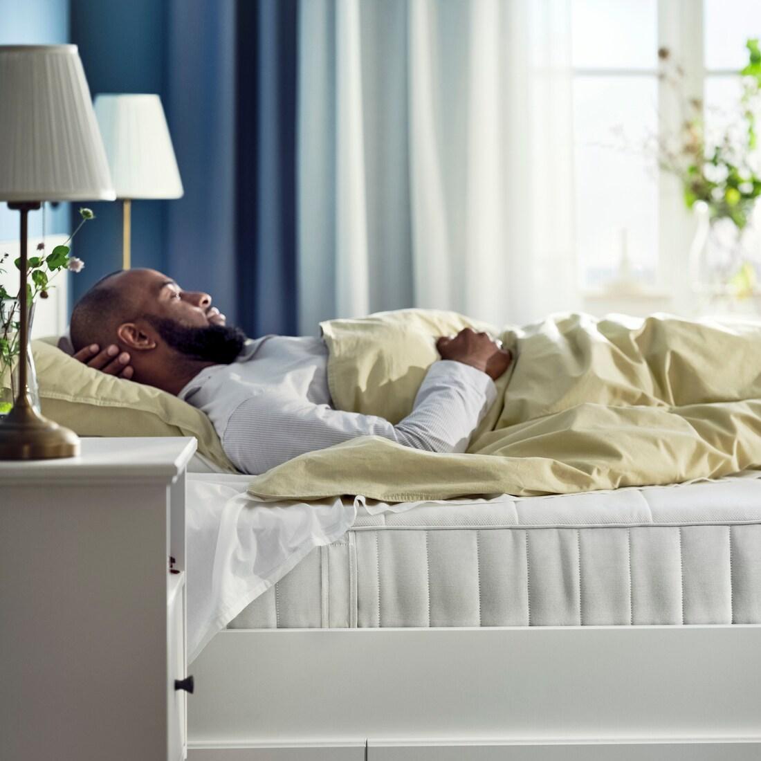 Un homme dort sur un VESTERÖY matelas.