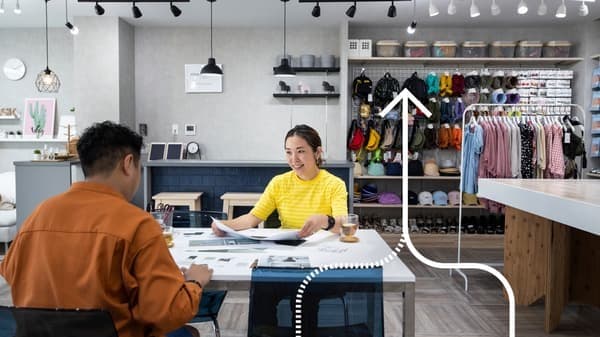 Un homme en chemise orange est assis à un bureau avec une collaboratrice IKEA