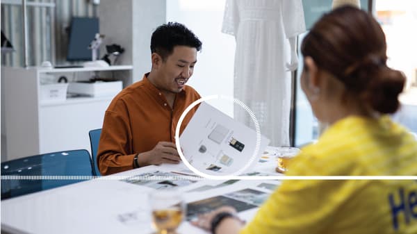 Un homme en chemise orange est assis à un bureau avec une collaboratrice IKEA