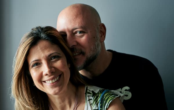 Un homme en t-shirt noir aux cheveux rasés enlace une femme aux cheveux marron méchés.