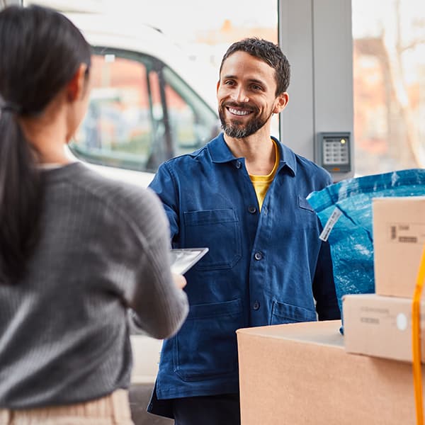 Un homme face à une femme avec des boîtes IKEA et un sac FRAKTA bleu. Il apporte des meubles et des accessoires pour son entreprise.