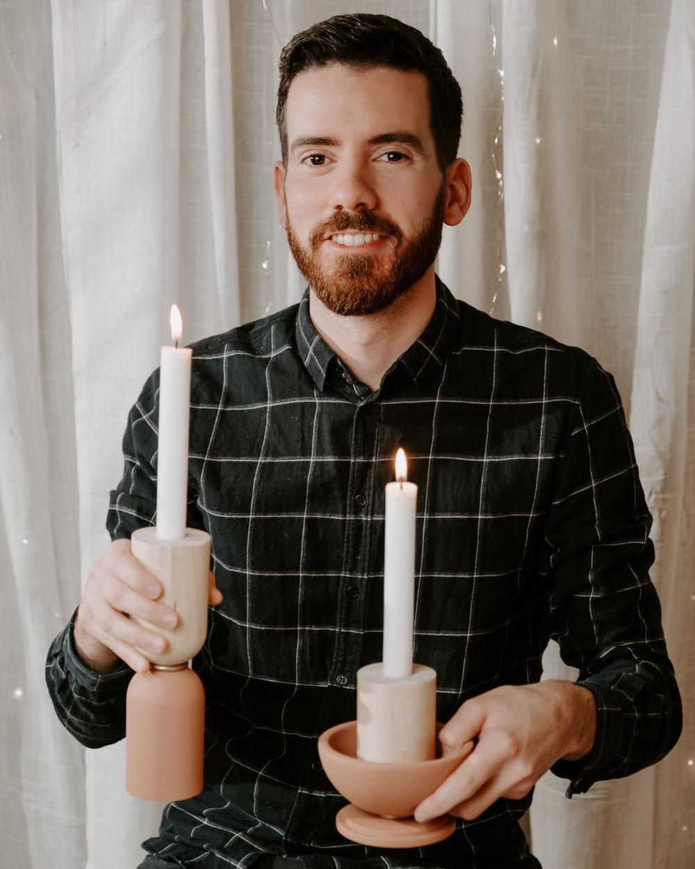 Un homme tient dans sa main deux bougeoires avec deux bougies allumées