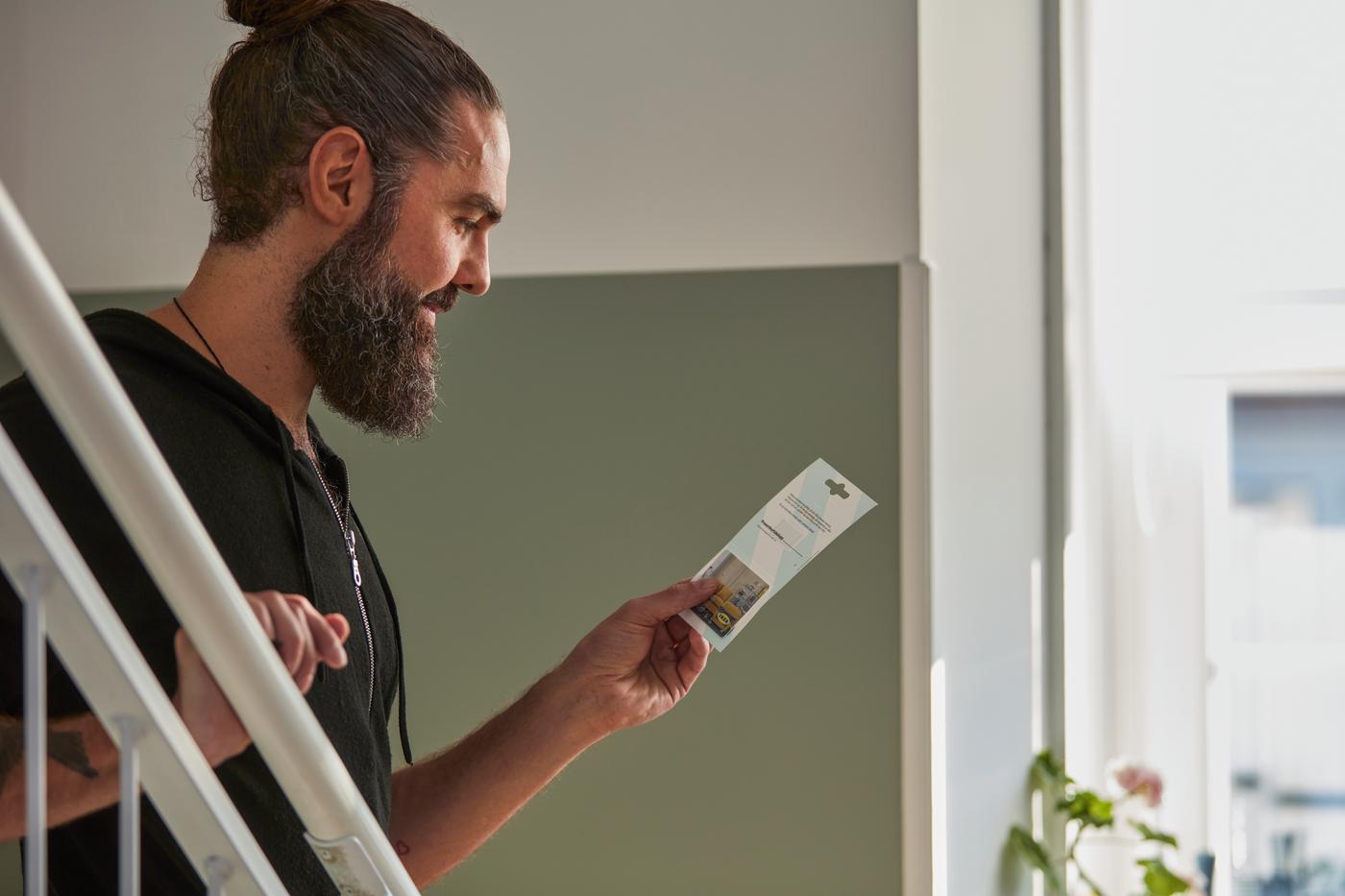 Un homme tient une carte-cadeau IKEA.