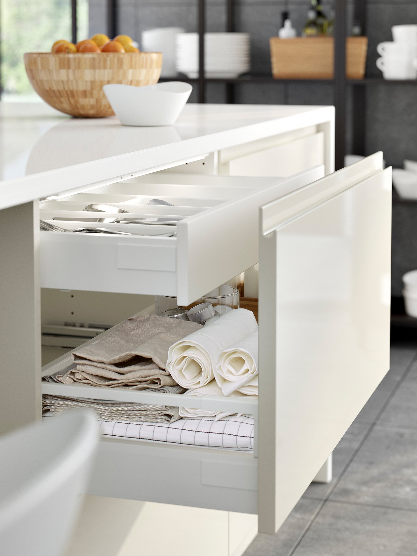 Un îlot brillant avec un tiroir ouvert, révélant un tiroir interne et divers éléments tels que du linge de table.