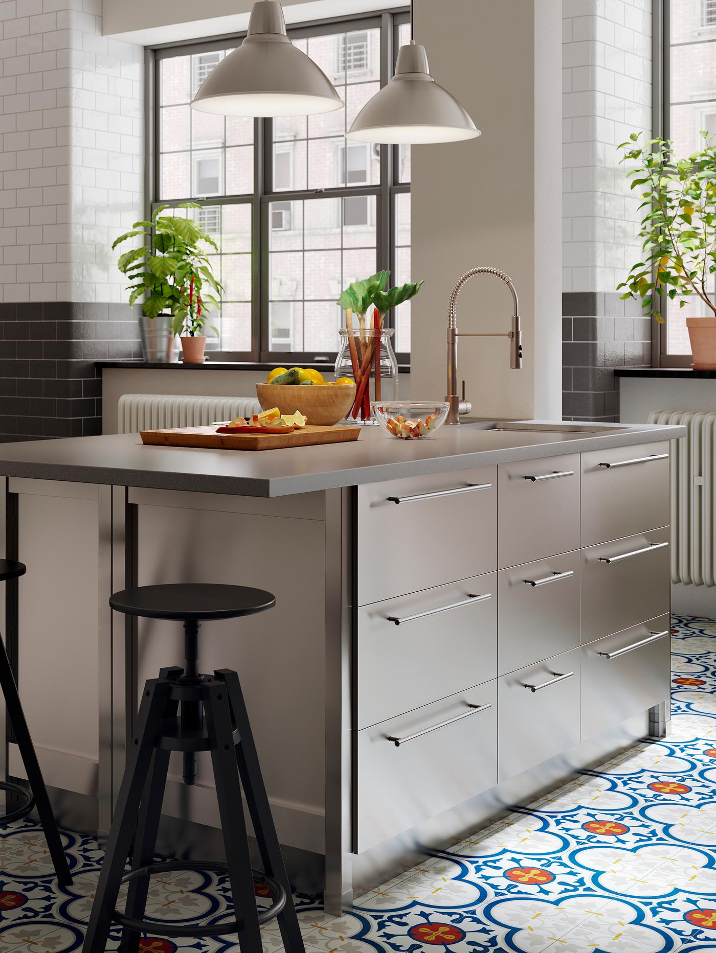 Un îlot de cuisine avec un comptoir à effet de béton/quartz et des façades de tiroir en acier inoxydable.