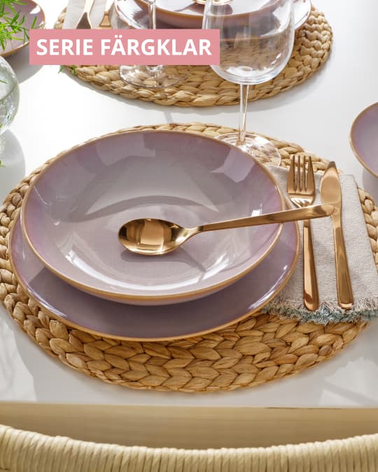 Un individual de mimbre y sobre él dos platos rosados de la Serie FÄRGKLAR.