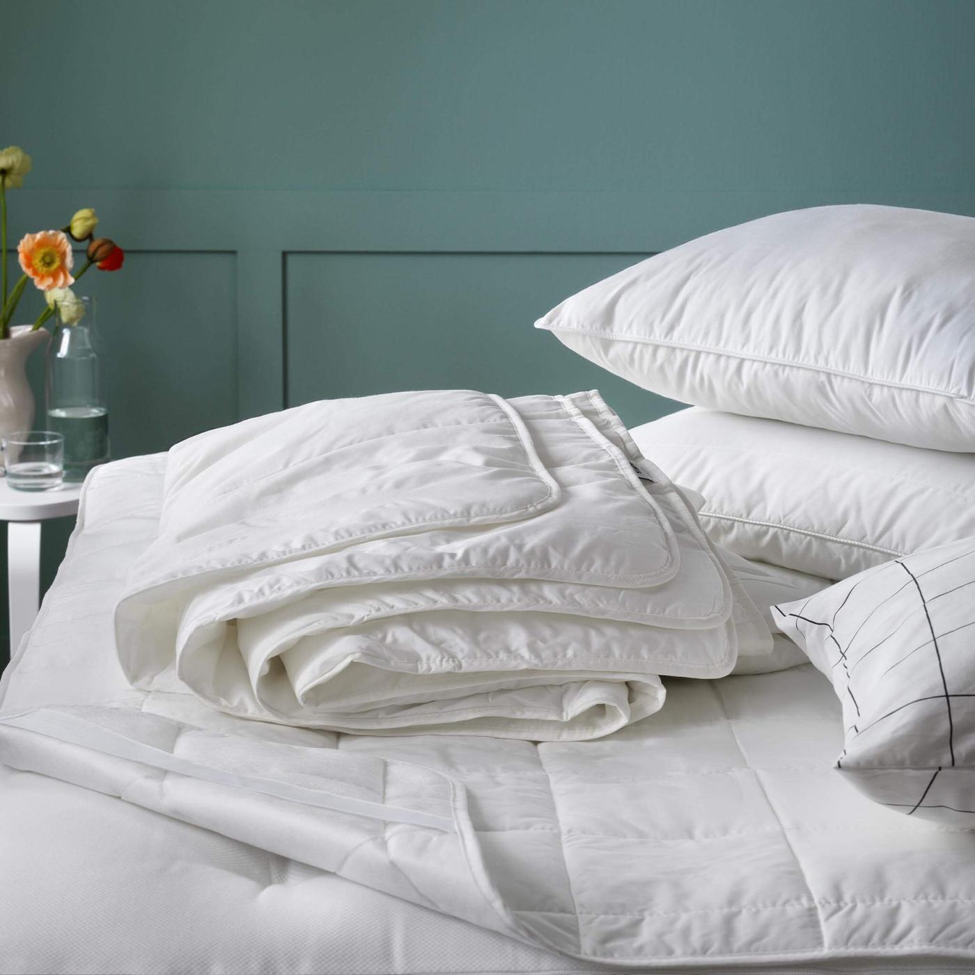 Un inserto blanco duvet en una cama con blanco almohadas siguiente a él.