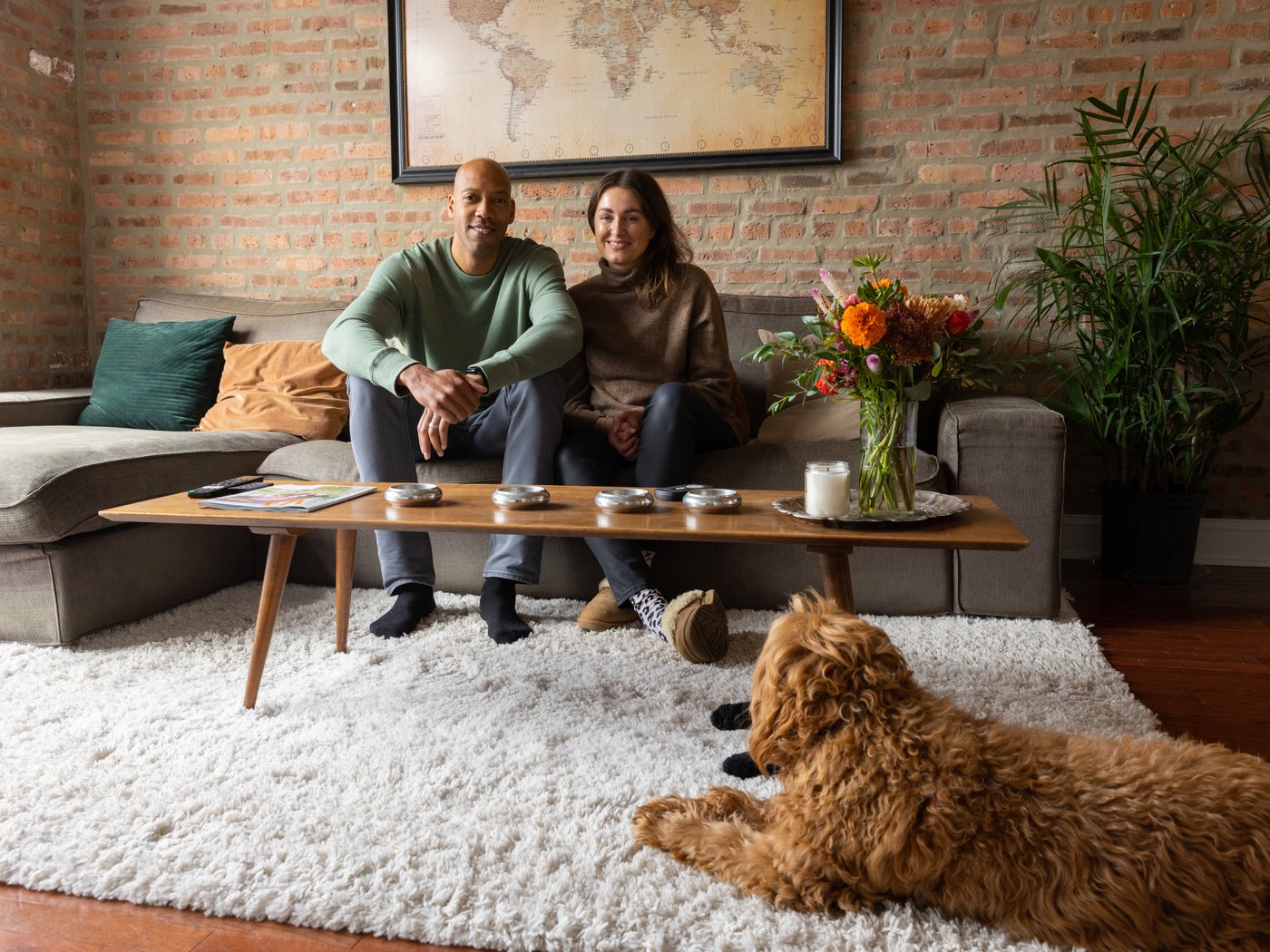 Un jeune couple assis sur un canapé sectionnel dans un salon avec un chien couché au premier plan