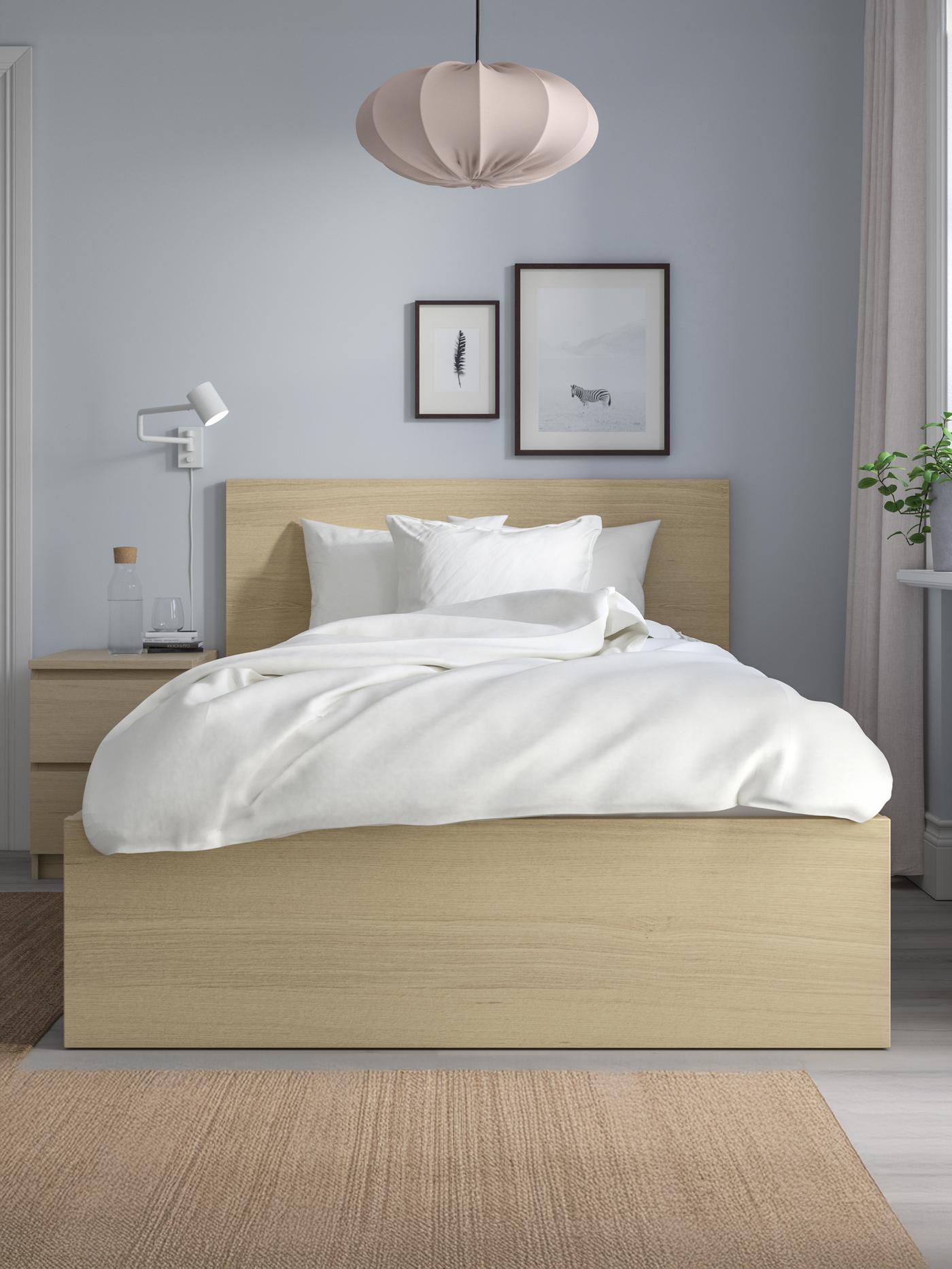 Un letto ad una piazza e mezzo in legno con biancheria bianca