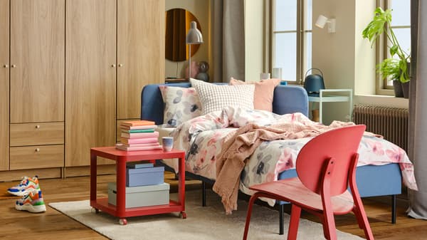 Un letto BLÅKULLEN blu con testiera angolare preparato con biancheria da letto LAPPNYCKLAR in una stanza luminosa - IKEA.
