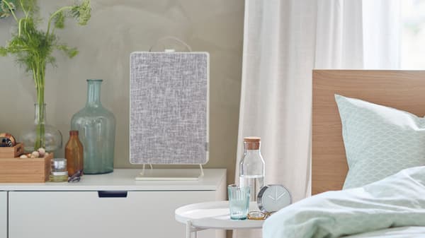 Un letto davanti a una finestra, vicino a una cassettiera con sopra un purificatore d’aria FÖRNUFTIG - IKEA