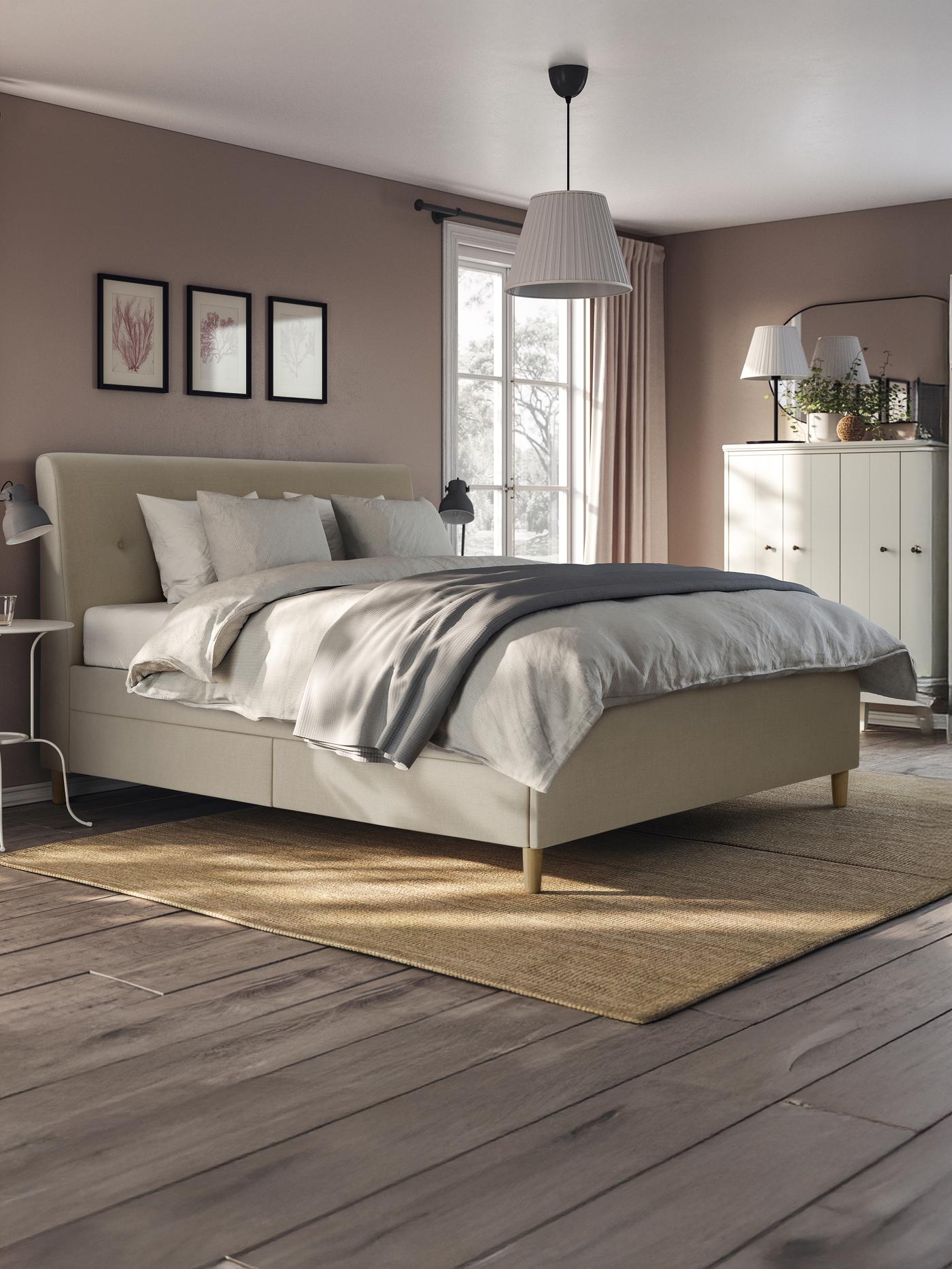 Un letto imbottito matrimoniale all'interno di una camera da letto con un tappeto e una portafinestra sullo sfondo