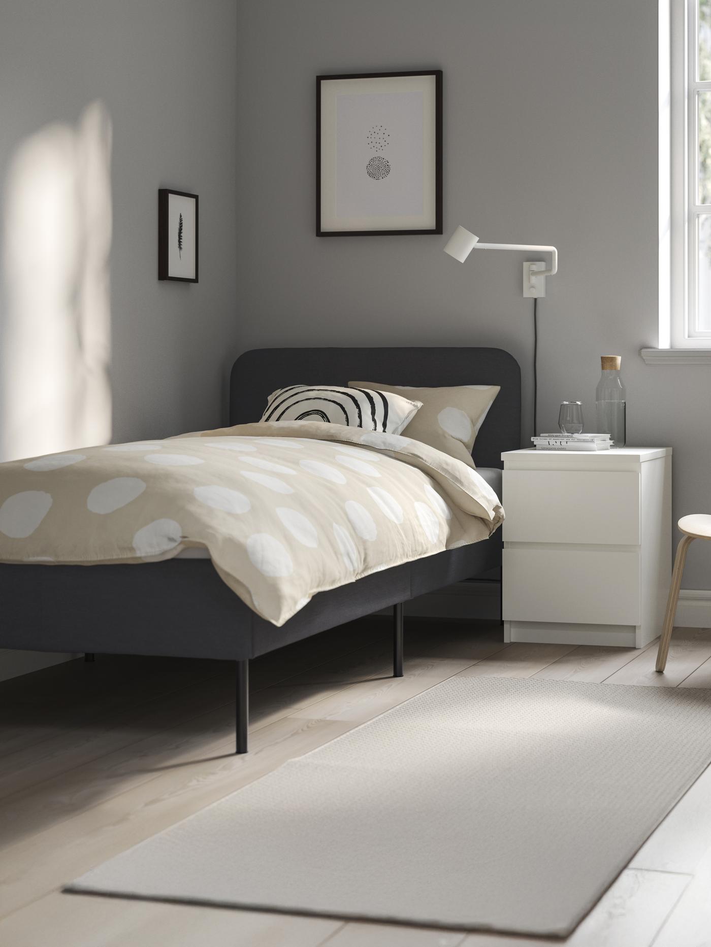 Un letto singolo con accanto un comodino con due cassetti.