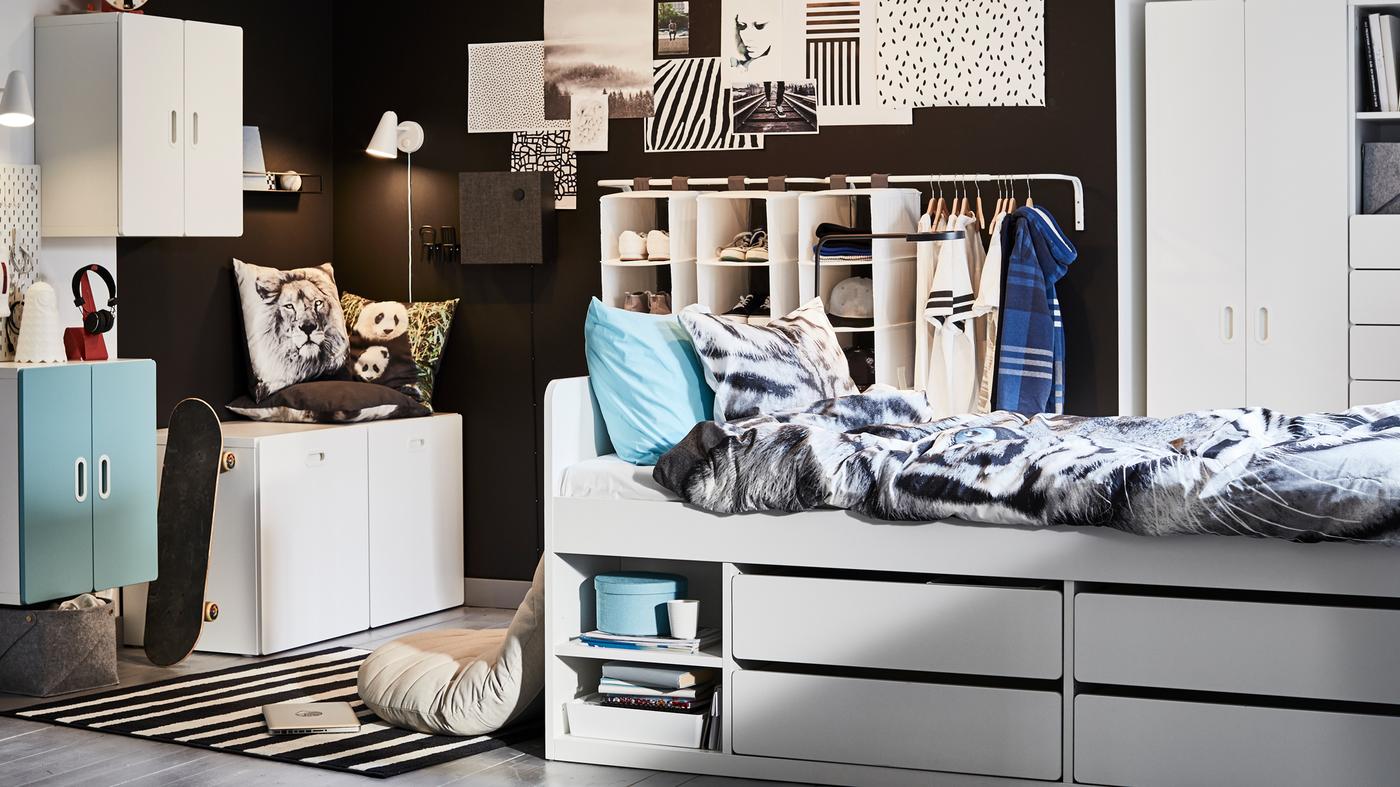 Un lit blanc SLÄKT avec rangement et linge de lit URSKOG à motif tigré au milieu d’une chambre d’enfant.