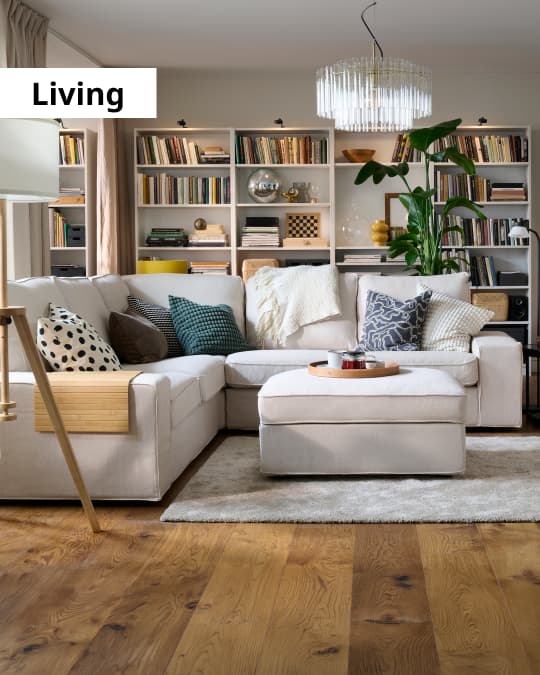 Un living con un sofá en L y detrás dos grandes libreros.