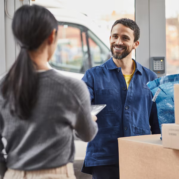 Un livreur livre un colis à une femme devant chez elle.