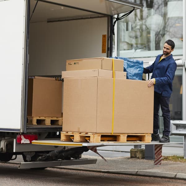 Un livreur qui descend des cartons de son camion de livraison.