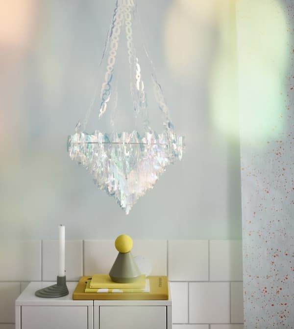 Un llum de sostre VINTER 2017 d'IKEA de plàstic i peces iridescents que semblen vidres a una habitació.
