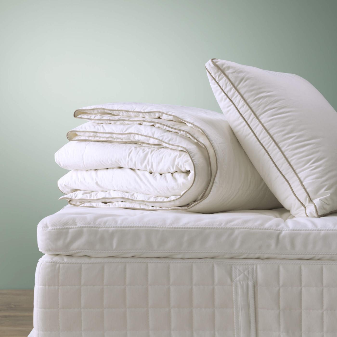 Un matelas avec une pile de linge de lit blanc dessus.