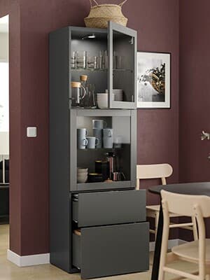 Un meuble de rangement BESTA dans une salle à manger. Les deux portes du haut sont des vitrines SINDVIK laissant voir l'intérieur. 