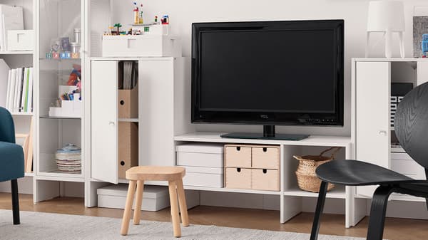 Un meuble télé BAGGEBO en bois blanc, dans un salon avec du décor neutre.