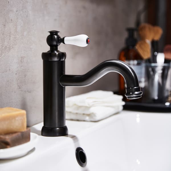 Un miscelatore nero su un lavabo bianco su cui sono appoggiate delle saponette e delle salviette bianche.