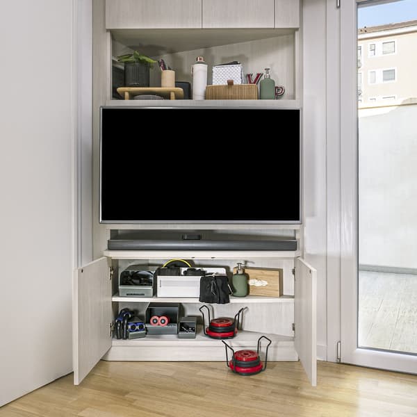 Un mobile bianco con un televisore al suo interno e sotto dei ripiani con Contenitore grigio-verde REJSA con oggetti sportivi all'interno.