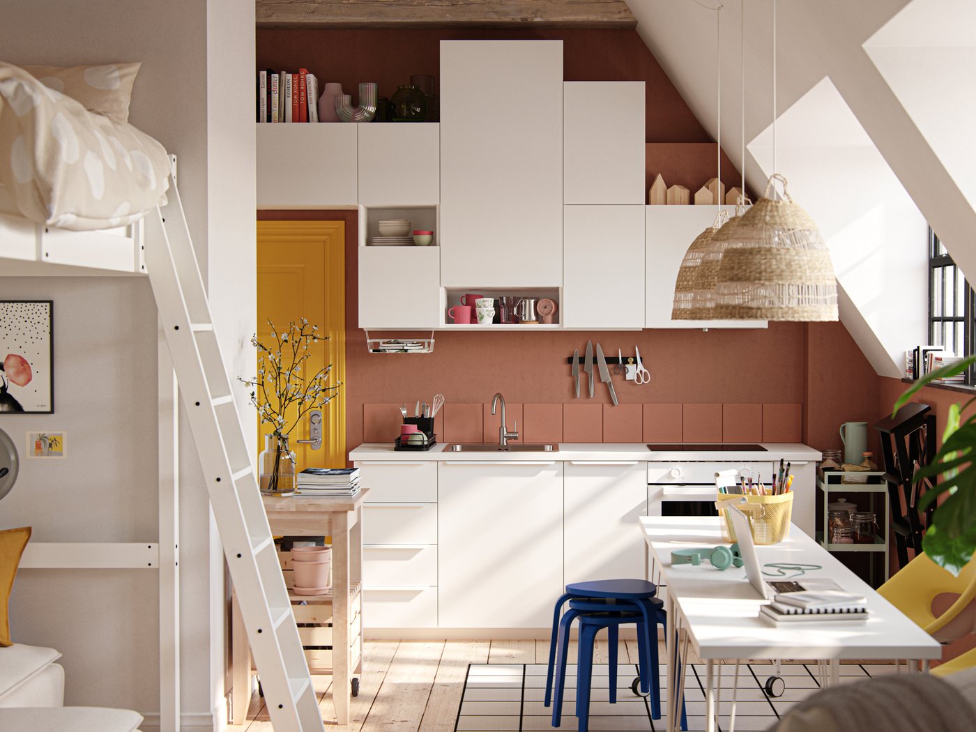 Un monolocale con soffitto spiovente, finestre in stile industriale, pareti color terracotta scuro e frontali per cucina VALLSTENA bianchi.
