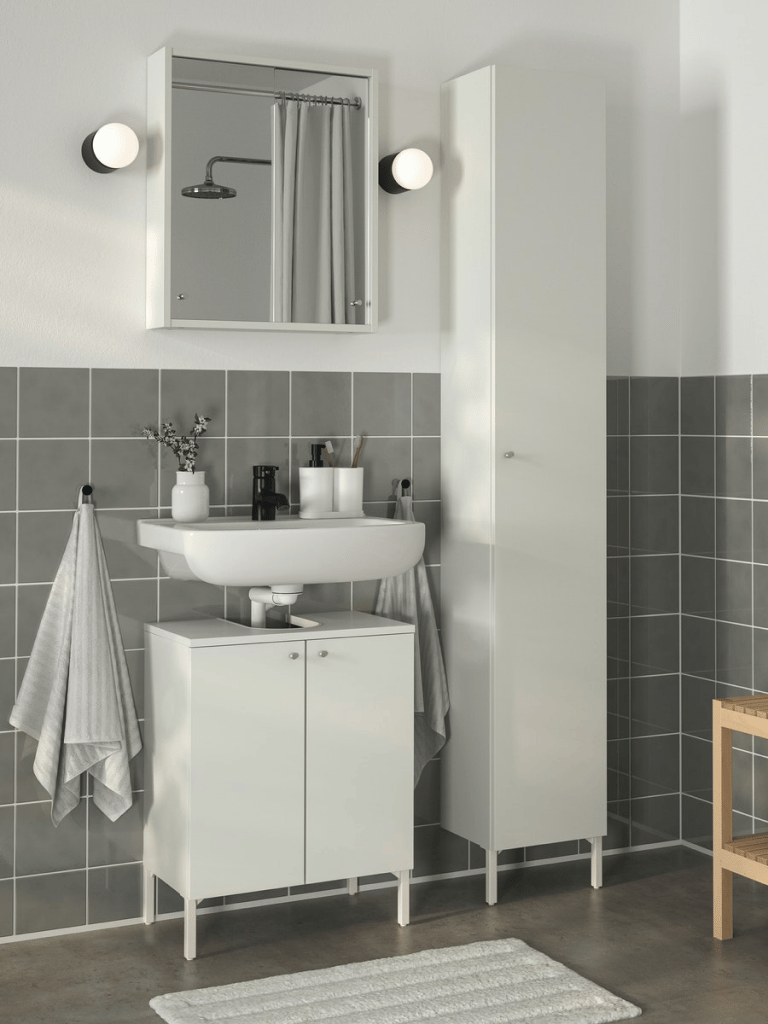 Un mueble de lavabo en un baño contra una pared de azulejos verdes.