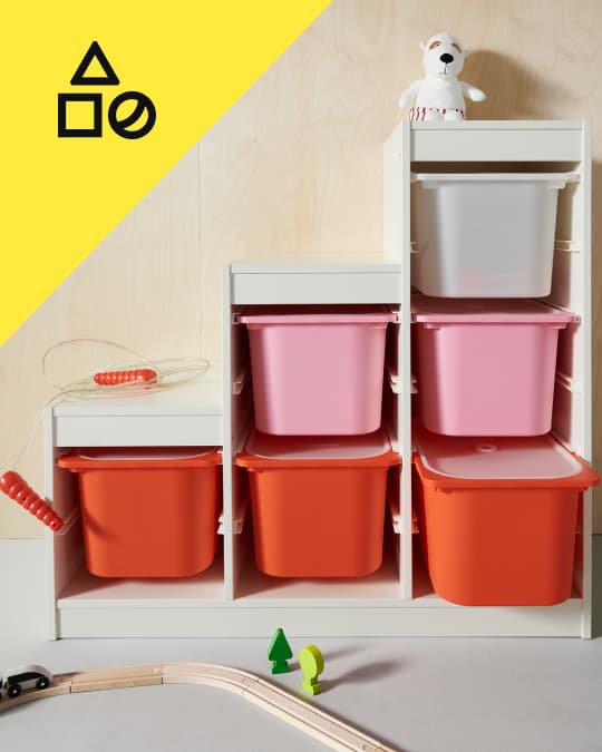 Un mueble para juguetes TROFAST con cajas plásticas de color rosa y naranja.
