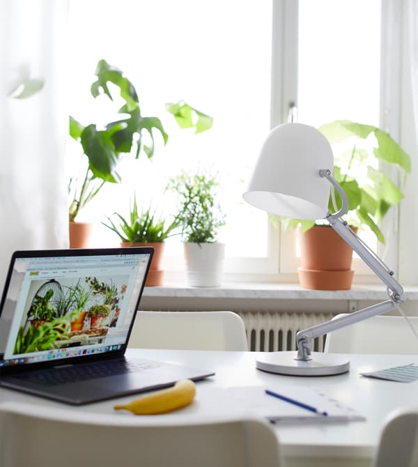 Un ordinateur portable et une lampe de table sont posés sur la table, utilisée comme espace de travail. 