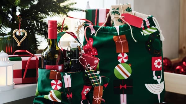 Un pacchetto e una sacca con i regali di natale affianco all'albero. 