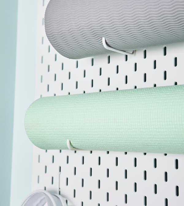 Un pannello portaoggetti SKÅDIS con tappeti arrotolati.