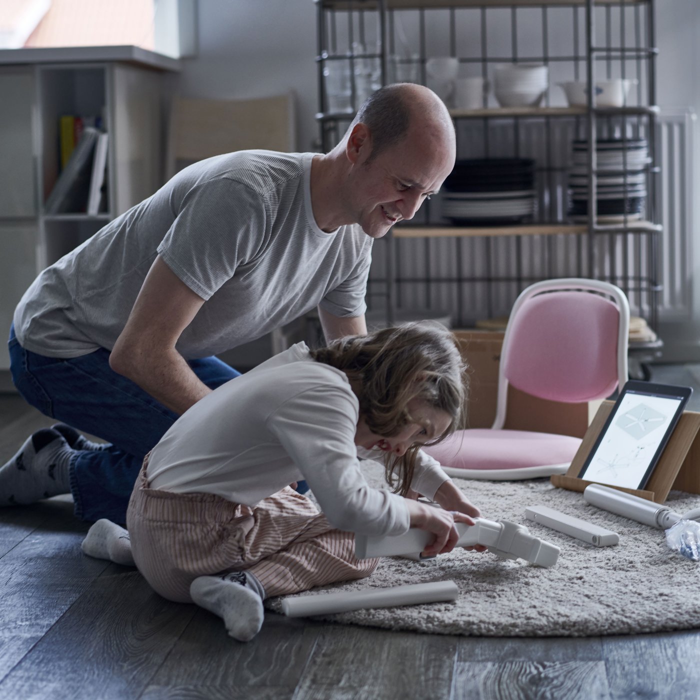 Un papa qui aide sa fille à monter un meuble IKEA.