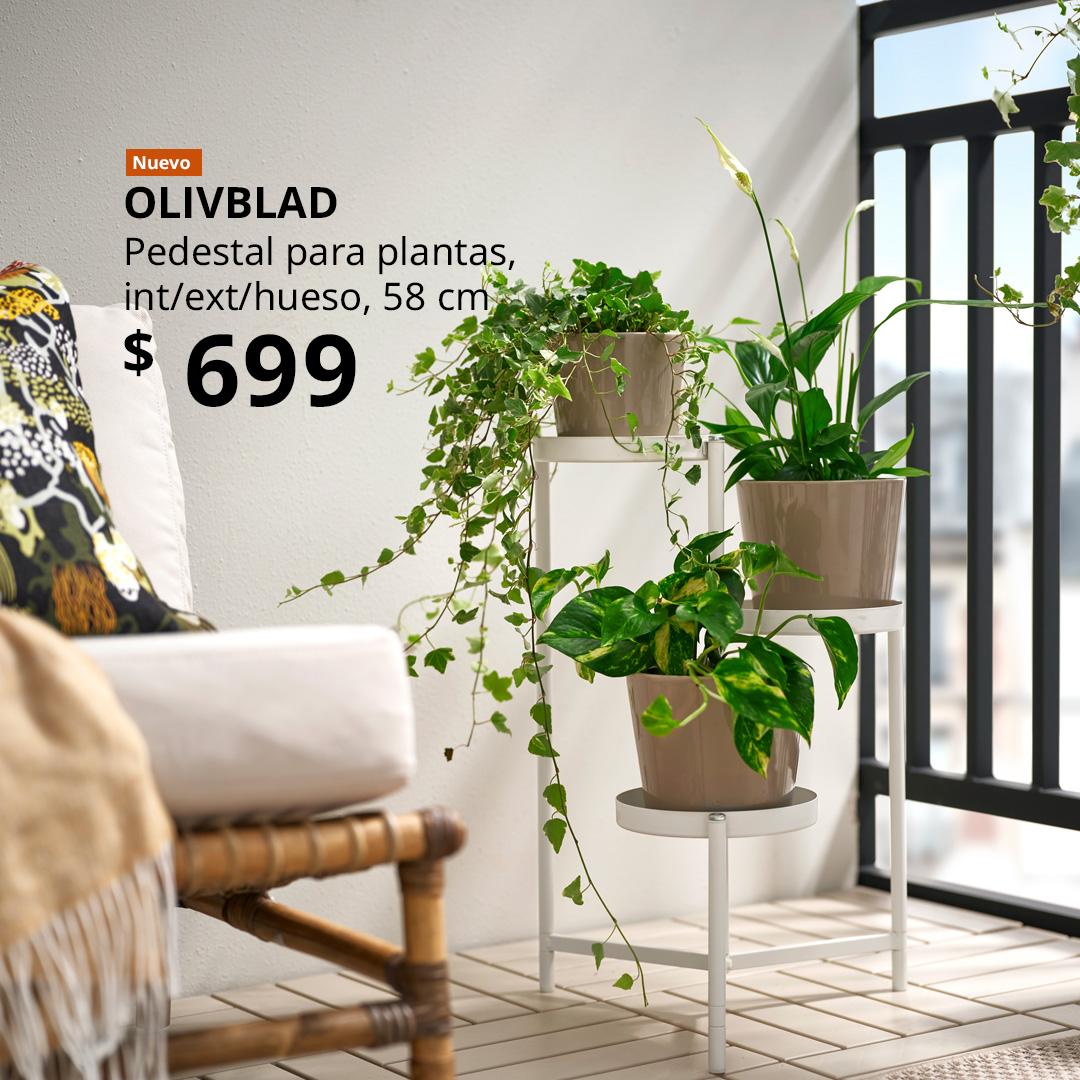 Un pedestal para plantas OLIVBLAD en color hueso para interior y exterior, con varias macetas colocadas en un balcón.