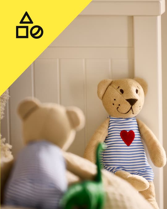 Un peluche IKEA frente a otro peluche en un dormitorio para niños.