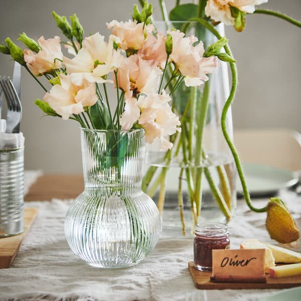 Un pequeño florero transparente se llena de flores recién cortadas en una mesa de boda