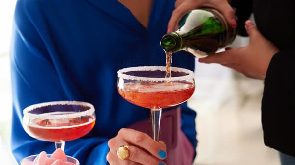 Un persona serve una bevanda a un altra persona col bicchiere in mano. 