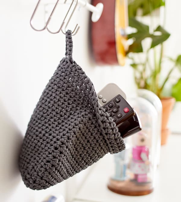 Un petit panier tressé accroché à une barre sert de rangement aux télécommandes.