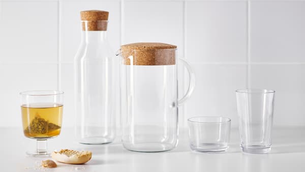 Un piano bianco con bicchieri, una caraffa e una brocca della serie IKEA 365+. A sinistra, un bicchiere pieno. 