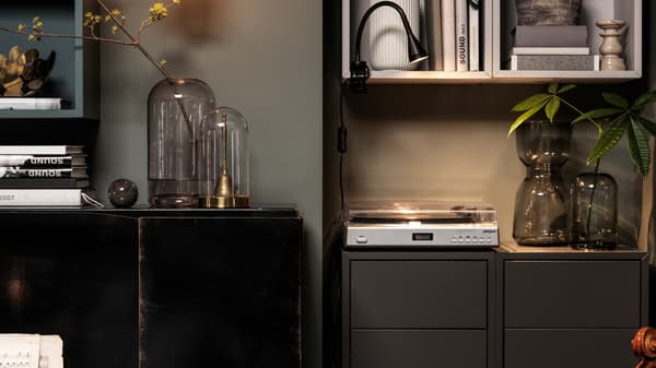 Un piano junto a una distribución vertical de gabinetes EKET. Un tocadiscos, libros y cristales decorativos decoran las superficies libres.