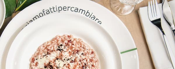 Un piatto con Riso carnaroli o riso rosa Marchetti, olio evo, sale, acqua, SYLT HJORTRON Confettura di camemoro, SYLT LINGON Confettura di mirtilli rossi, succo di lime, blue cheese, terra di radici fermentate e menta fresca per guarnizione.
