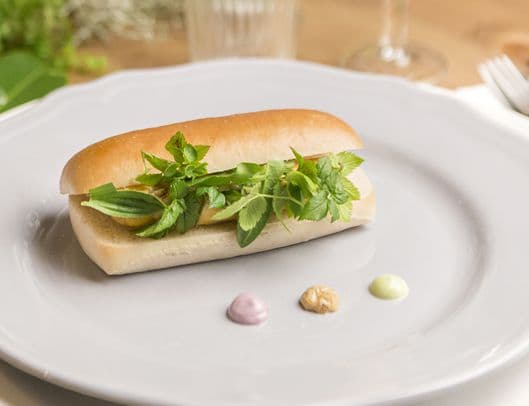Un piatto con un hot dog di salsiccia di salmone e accanto delle salse.