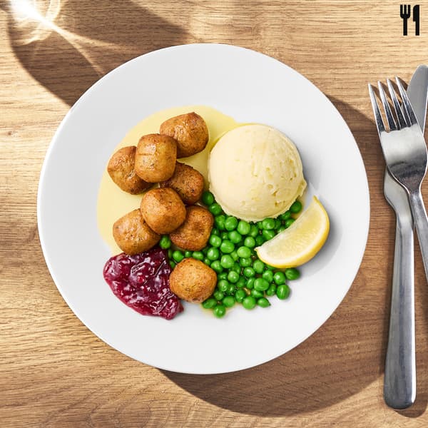 Un piatto di polpette  di pesce con purè, piselli e salsa ai mirtilli