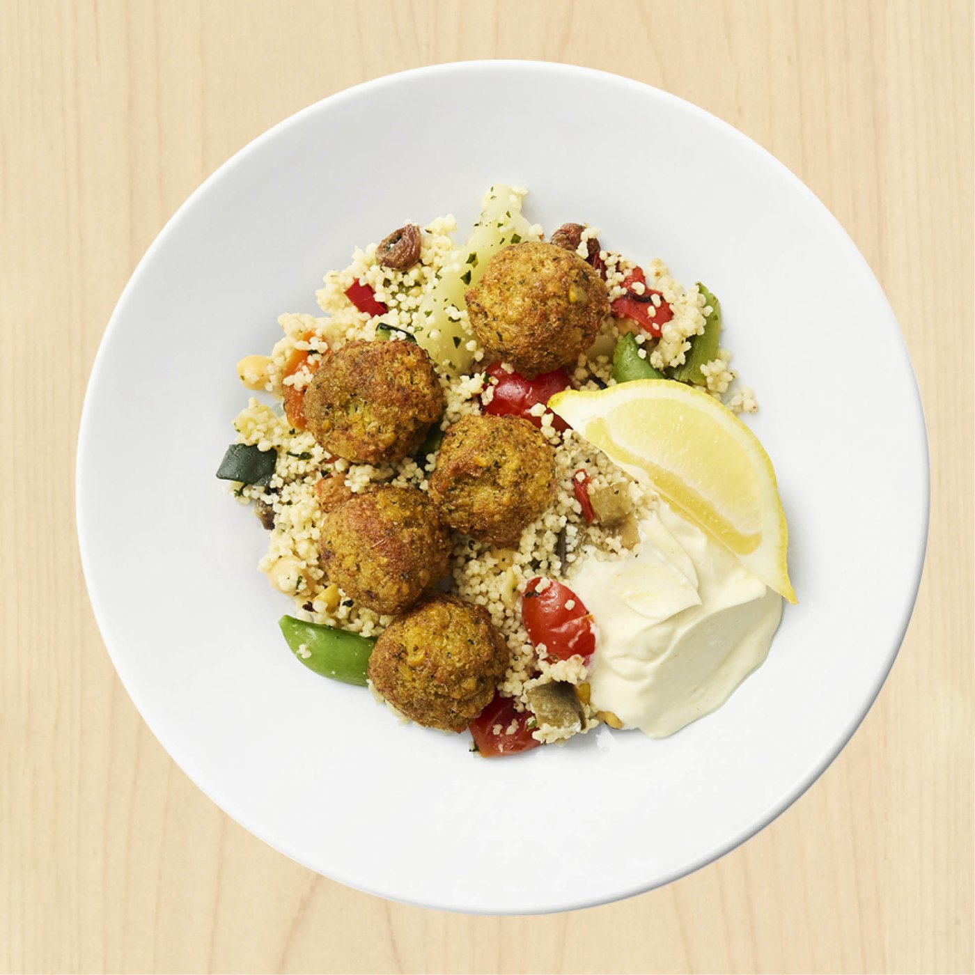 Un plat de boulettes végétales IKEA HUVUDROLL avec couscous et citron