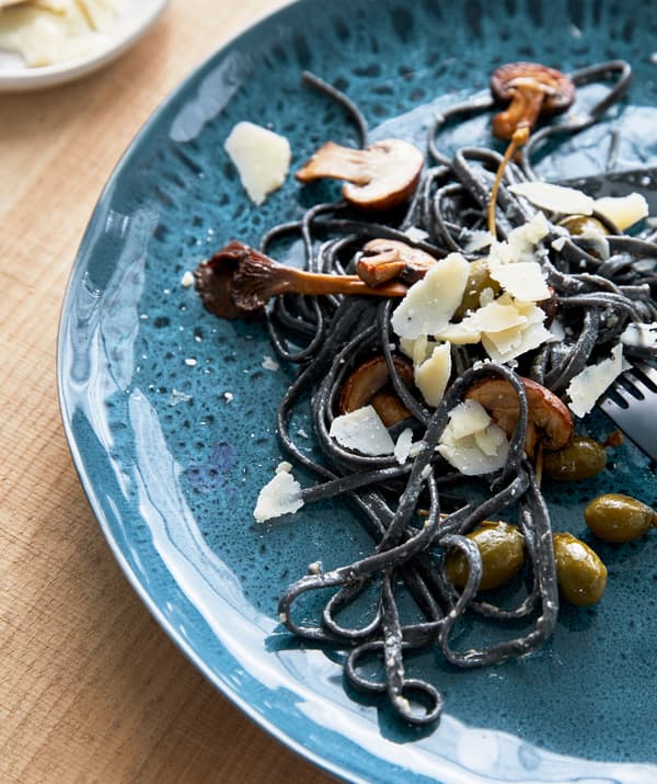 Un plato de pasta servido en un plato de color turquesa con un diseño moteado.