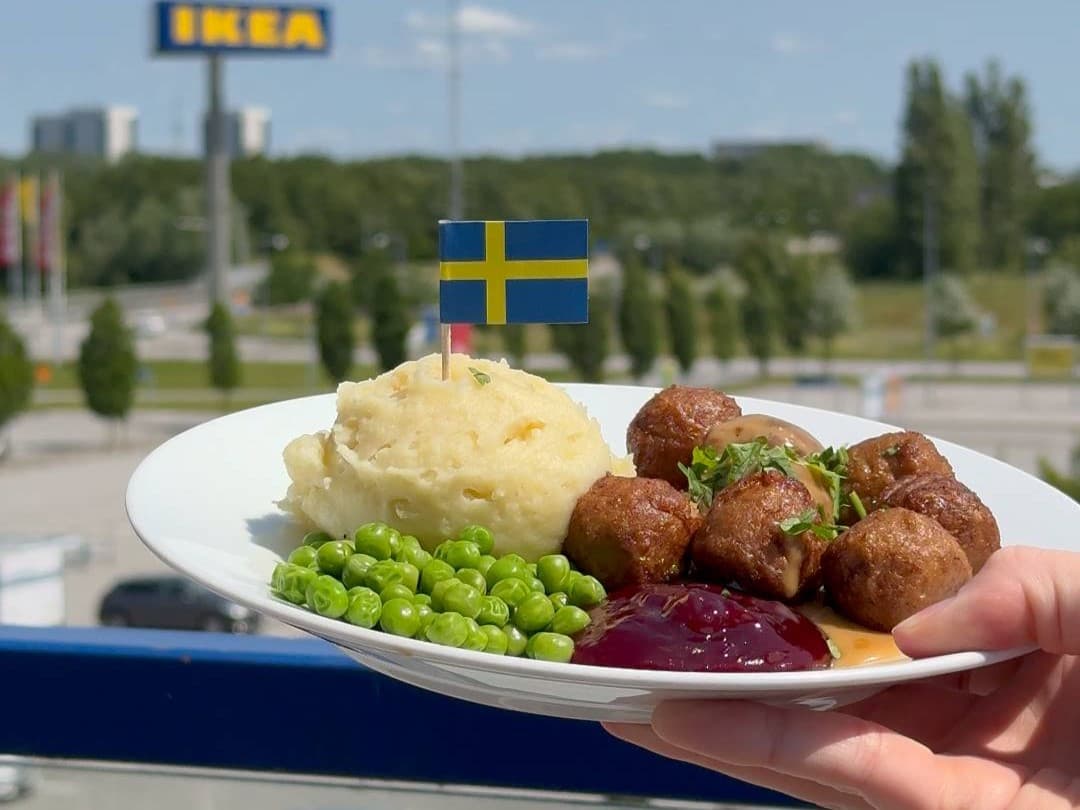 Un plato típico de IKEA con albóndigas suecas servido al aire libre con puré de patatas, guisantes y mermelada con una bandera de Suecia.