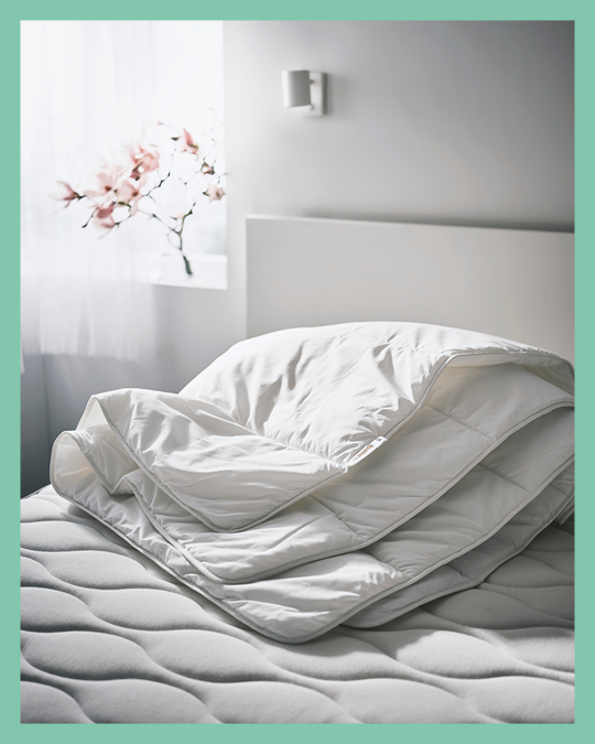 Un plumón blanco IKEA doblado sobre una cama.